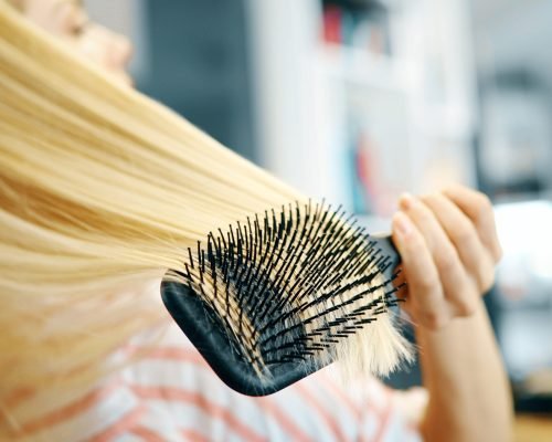 Attractive smiling beautiful woman brushing her hair