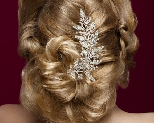 Beautiful blond girl with perfect skin, evening make-up, wedding hairstyle and accessories. Hairstyle back View. Picture taken in the studio.
